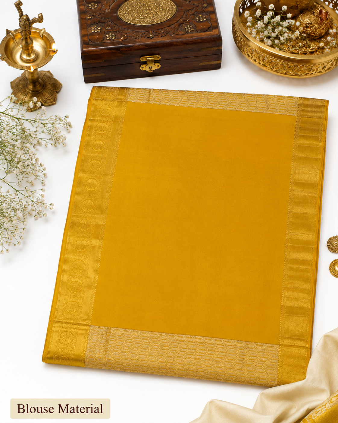 Mustard yellow saree with a wooden box and decorative items on a white background