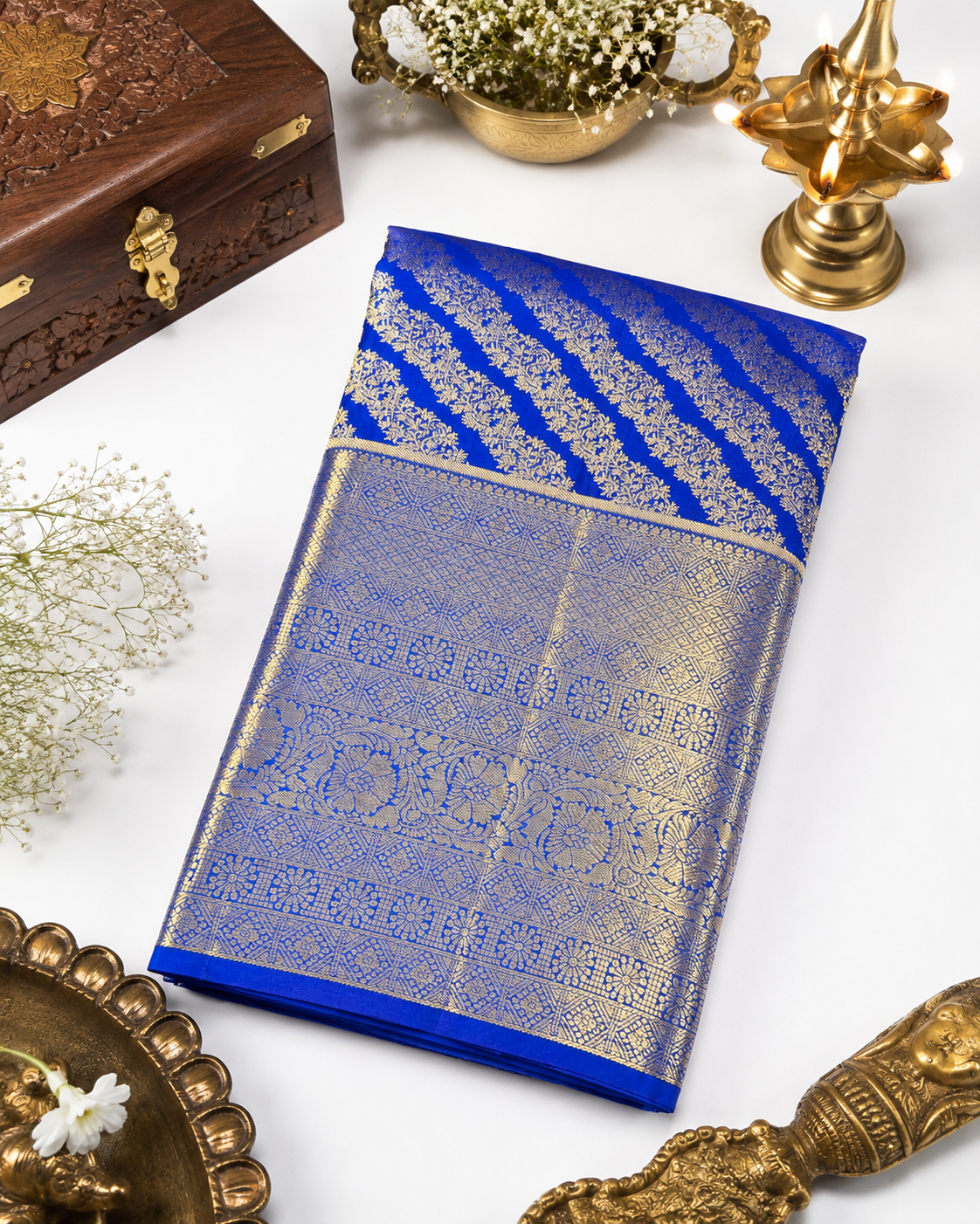 Blue saree with gold patterns on a white surface with decorative items.
