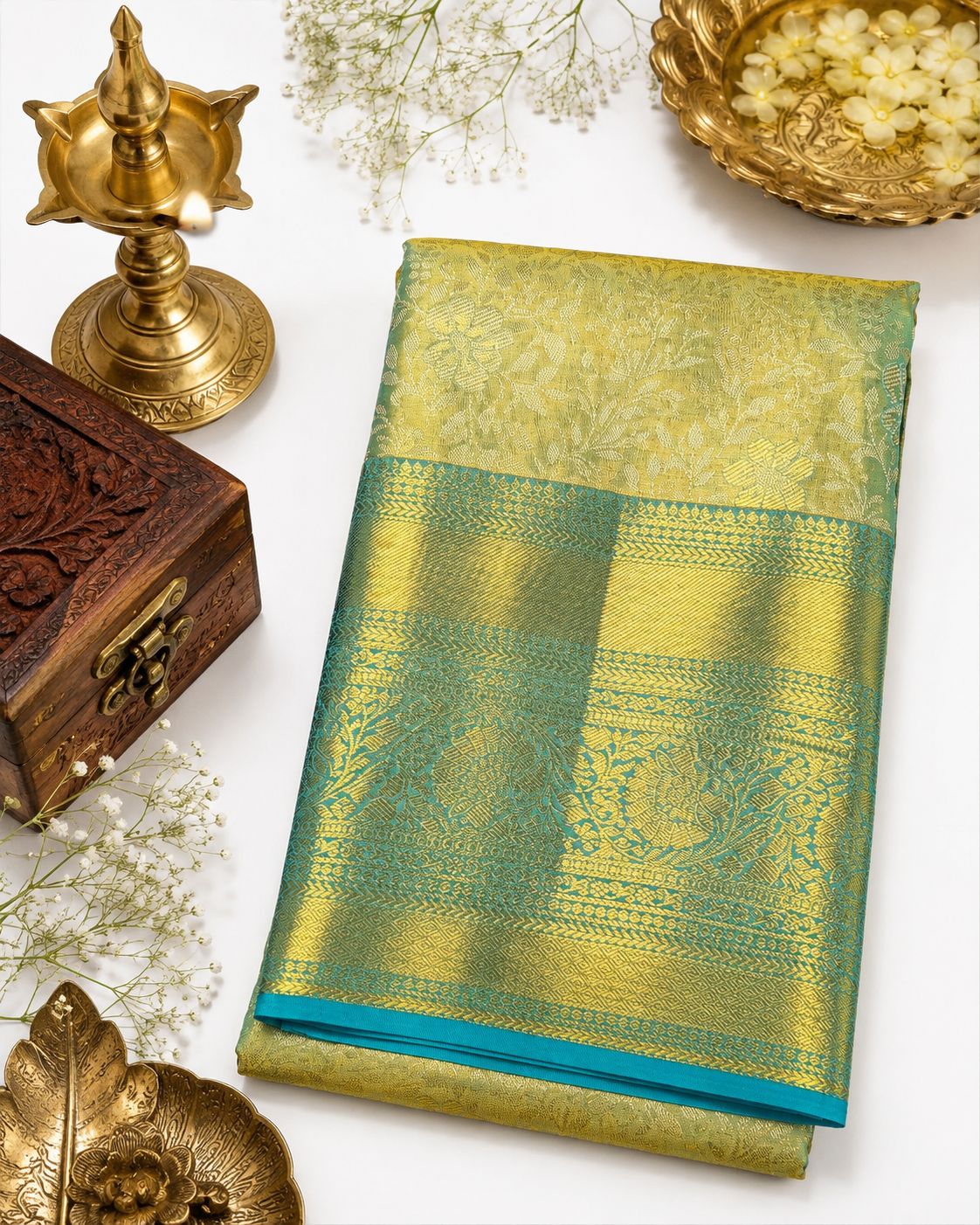 Green and gold saree with decorative items on a white background